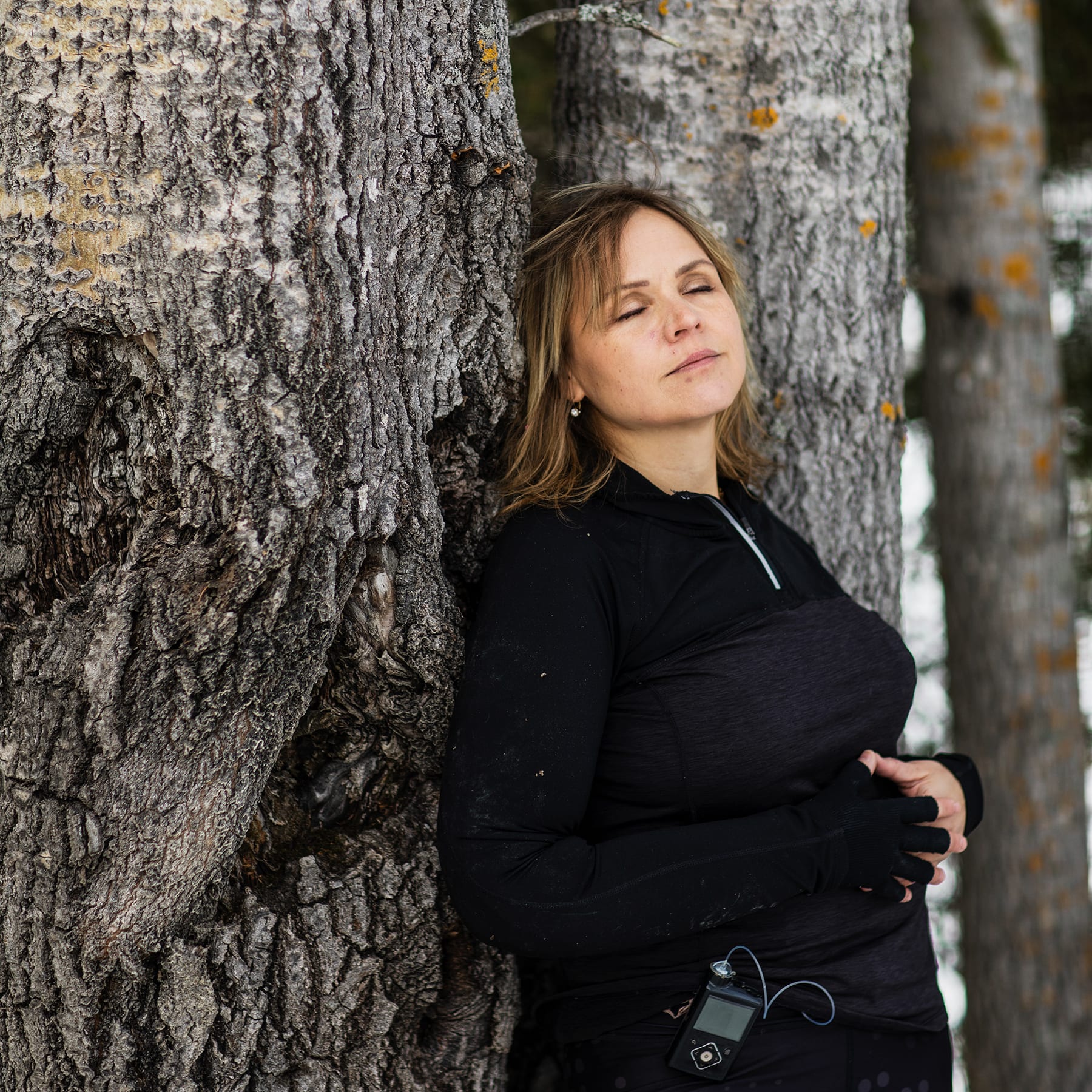Charlotta lutar sig mot en träd i skogen