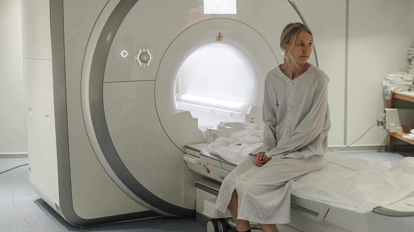 Kvinna sitter på brits vid magnetkamera
