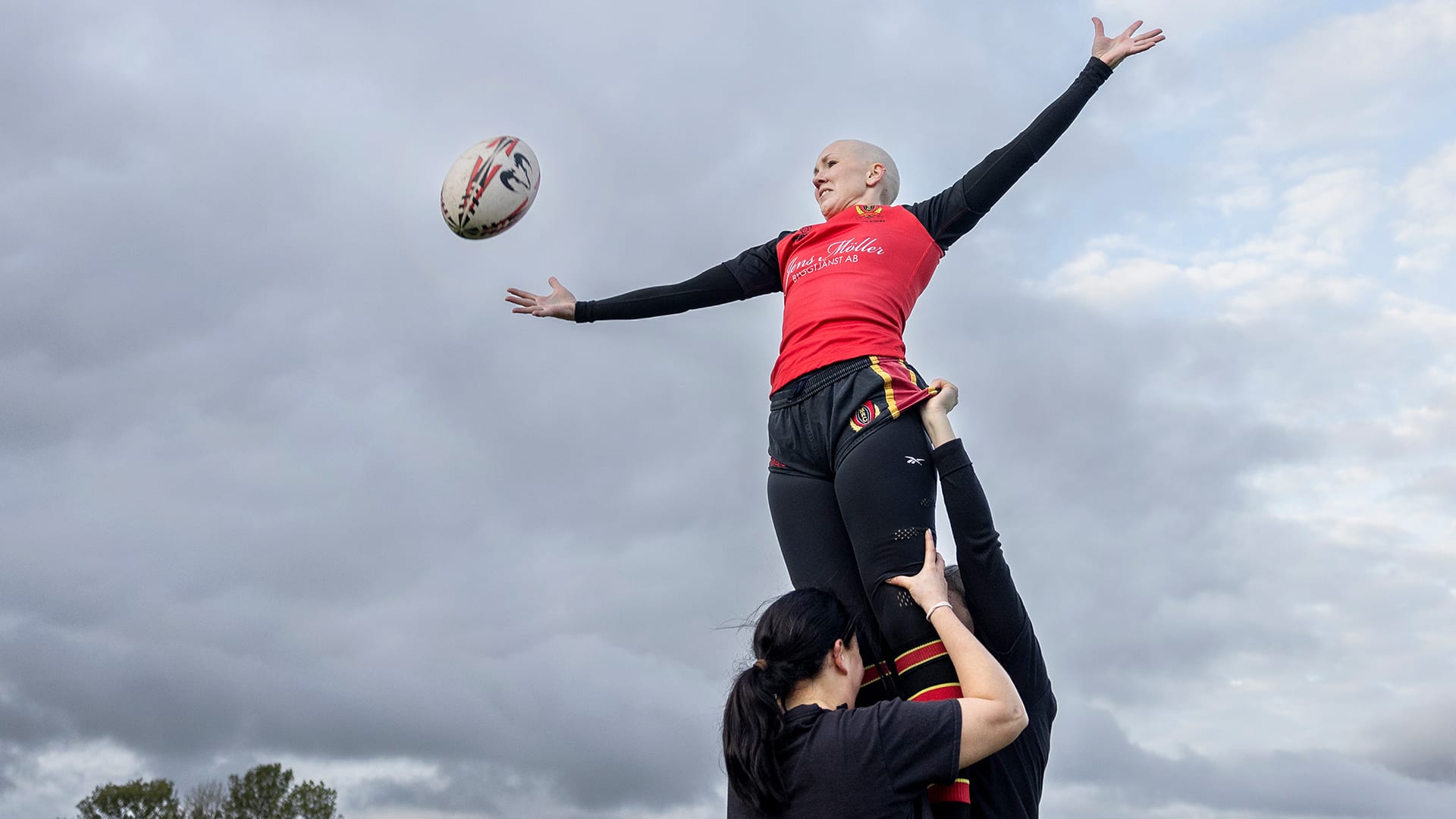 Rugbyspelaren Rebecka Sundell bär uppburen av sina lagkarater för att kunna fånga bollen som är på väg mot henne.