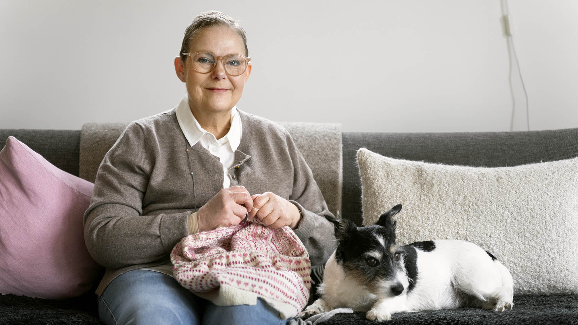 Cecilia Nilsson stickar i soffan med hunden Stella bredvid sig. Foto: Ola Torkelsson.