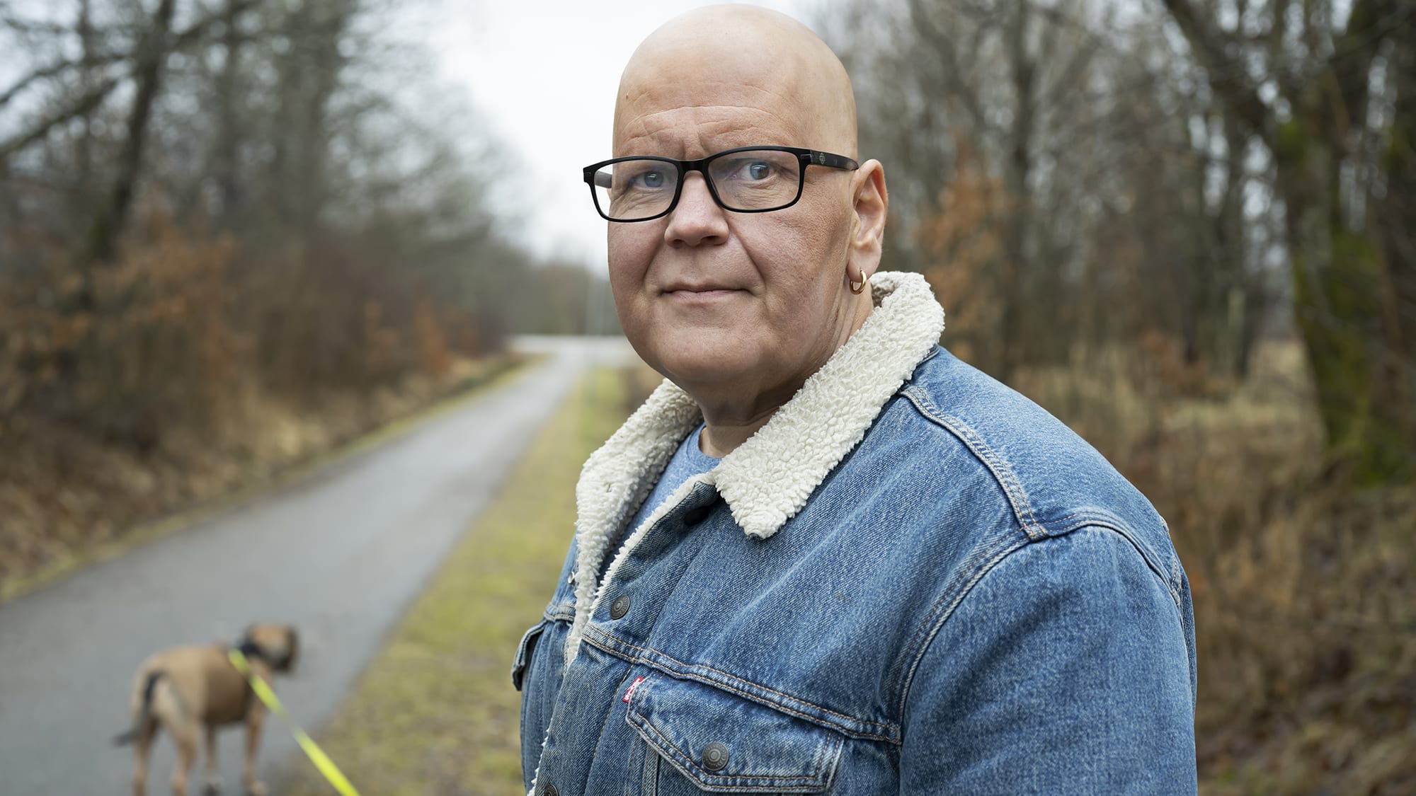 Liggande utomhusbild. Paul i halvfigur. Hunden i koppel syns på avstånd. Foto: Julia Sjöberg.