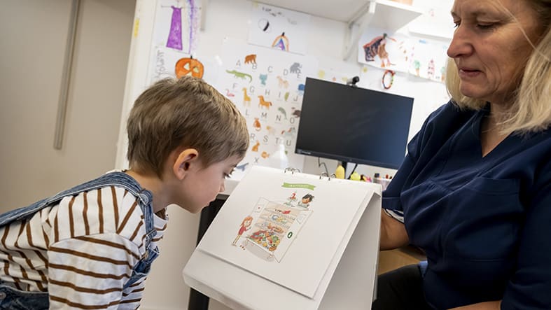 Pojke på barnavårdscentral med sköterska som visar Sagasagor