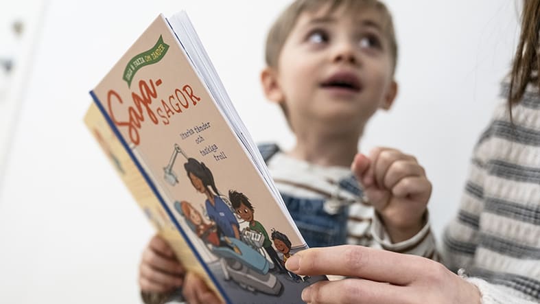 Pojke på barnavårdscentral med sköterska som visar Sagasagor