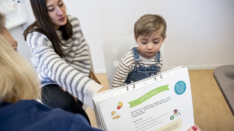 Pojke på barnavårdscentral med sköterska som visar Sagasagor
