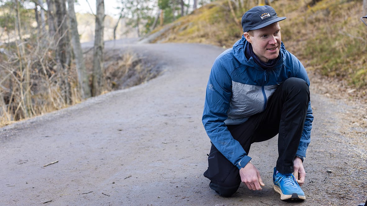 Marcus sitter på huk och knyter sina springskor