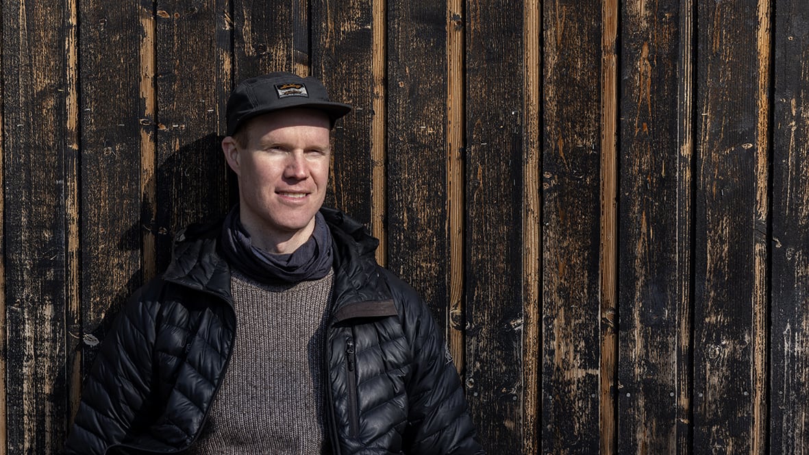 Porträtt av Marcus Aspsjö i keps lutad mot trä panel.