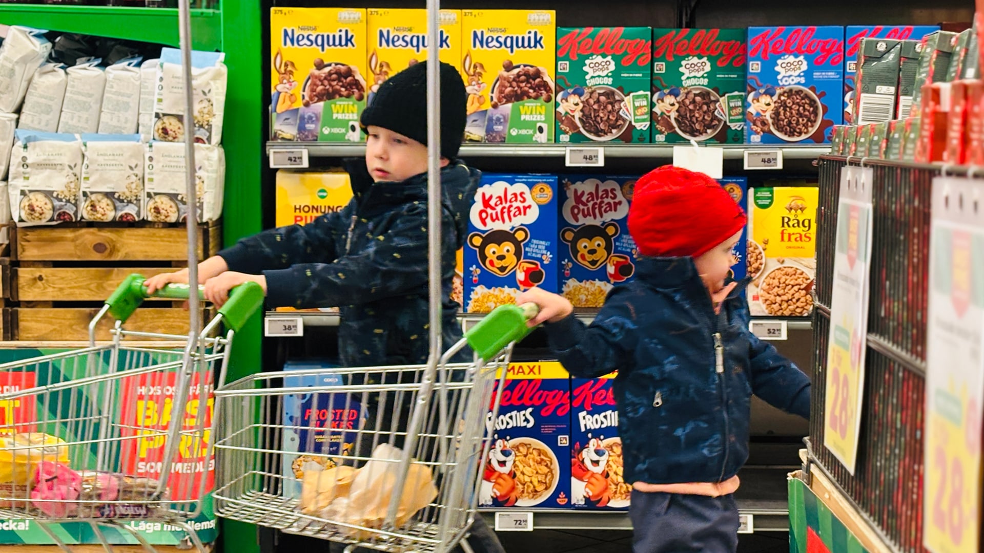 Två barn i en mataffär framför en hylla med frukostflingor