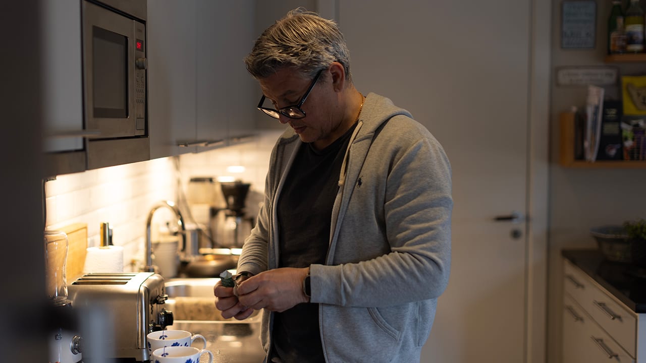 Medelålders man står i köket och gör te.