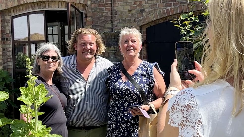 Man med kvinnor vid sin sida blir avporträtterade av kvinna med mobil