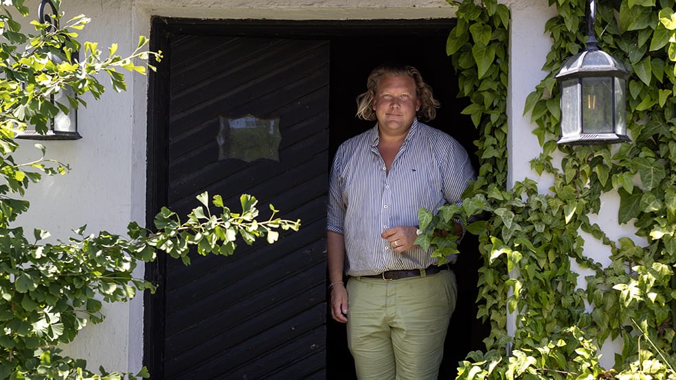 Man i dörröppning omgiven av grönska