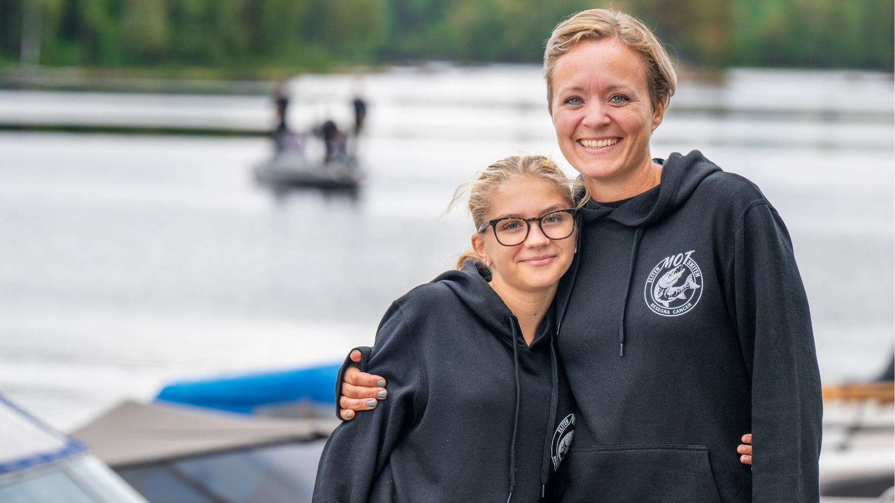 En tonåring och en av grundarna står sida vid sida framför sjö