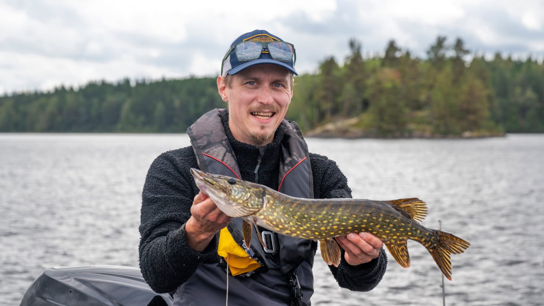 Man håller upp en gädda som han precis fångat.
