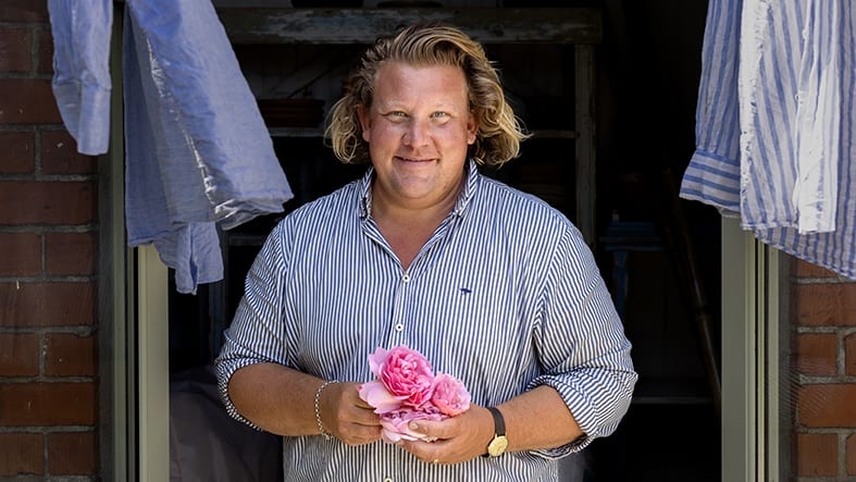 Man med blomma i handen tittar in i kameran