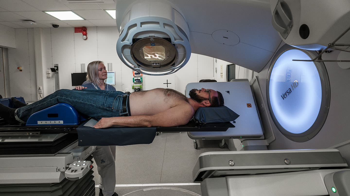 Man på brits i en strålapparat får strålbehandling