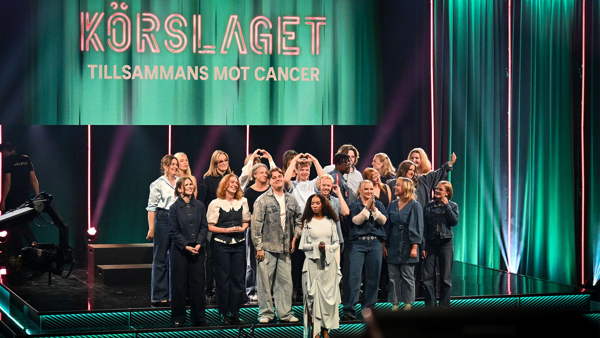 Gruppbild på en av körerna i Körslaget. Jesper gör ett hjärta med sina händer.