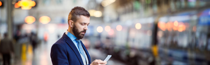 Homme sur le quai d’une gare consultant son téléphone intelligent.