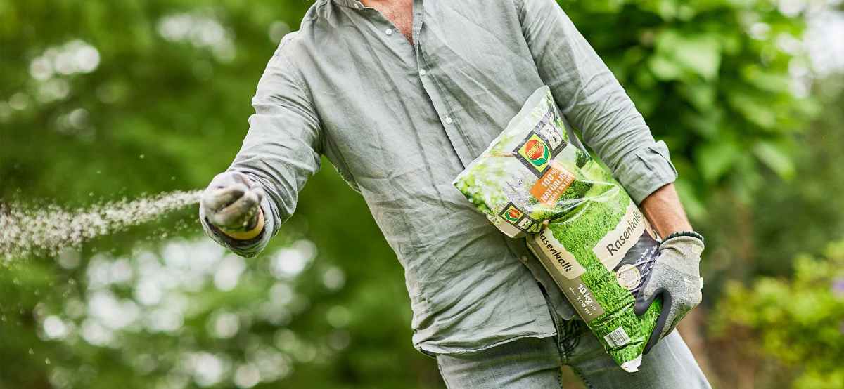 Mann kalkt den Rasen mit COMPO BIO Rasenkalk
