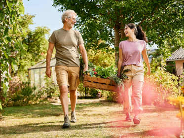 Zwei Personen tragen eine Kiste mit Gemüse