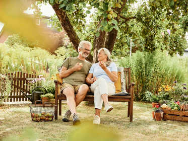 Zwei Personen sitzen auf einer Bank in einem Garten.