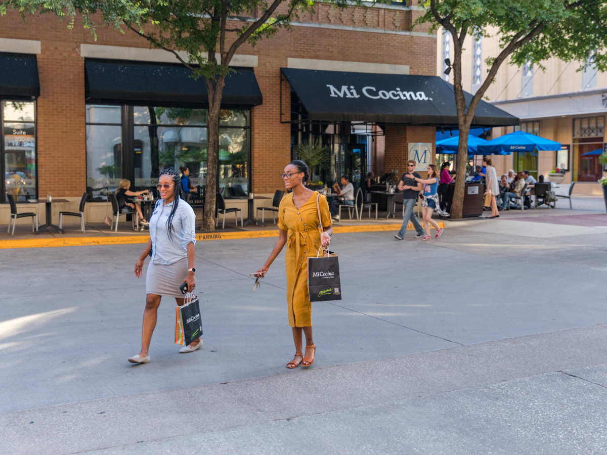Two women walking in front of Mi Cocina