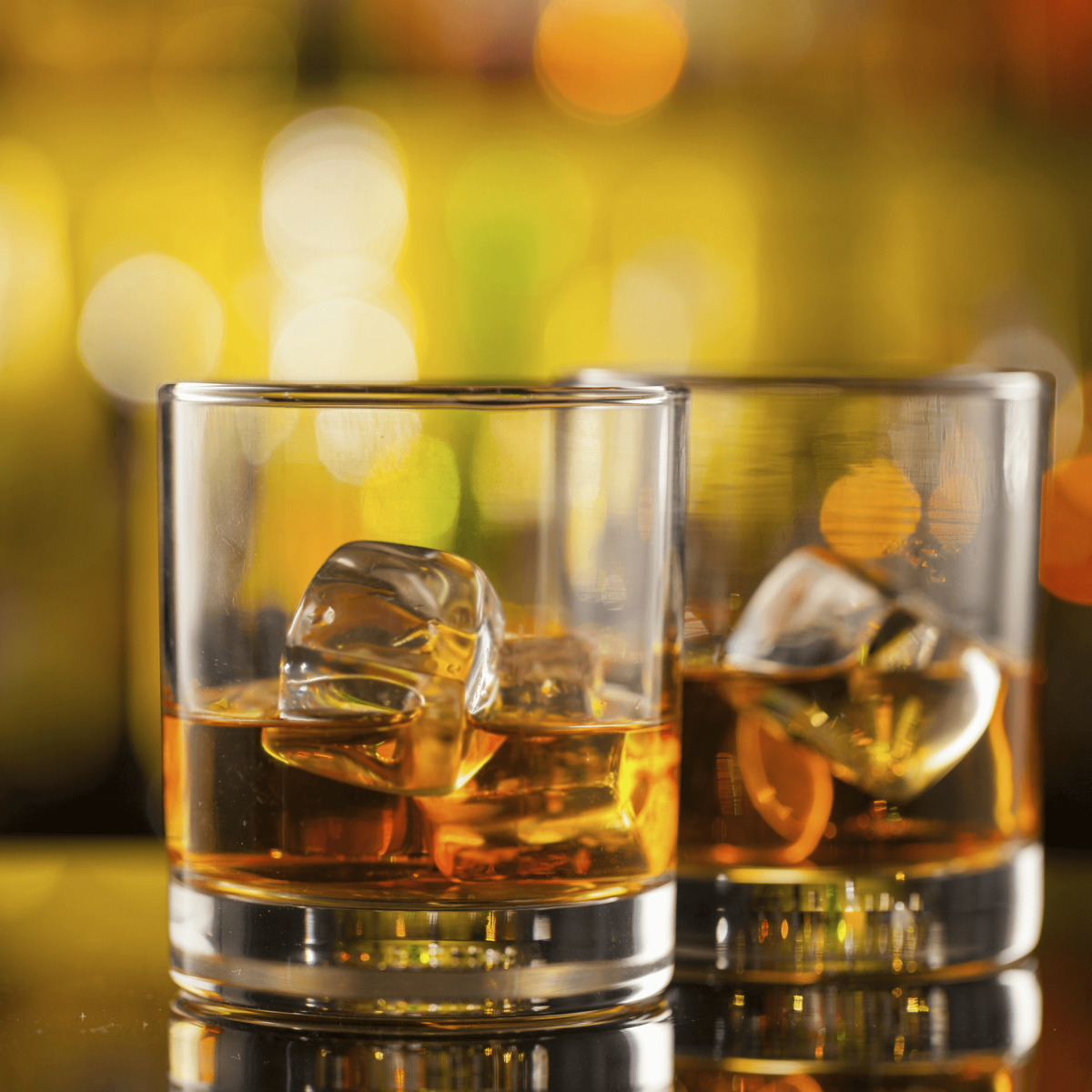 Two glasses of whiskey on a bar