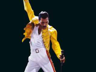Freddie Mercury of Queen singing on stage with fist raised