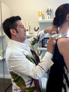 Daniel Esquivel pins and tucks a garment under construction during a fitting.