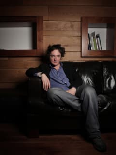 comedian and actor Dylan Moran sitting on a couch