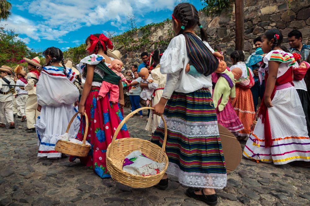 Soldaderas in the Mexican Revolution Day parade march with baskets and rebozo-wrapped baby dolls.