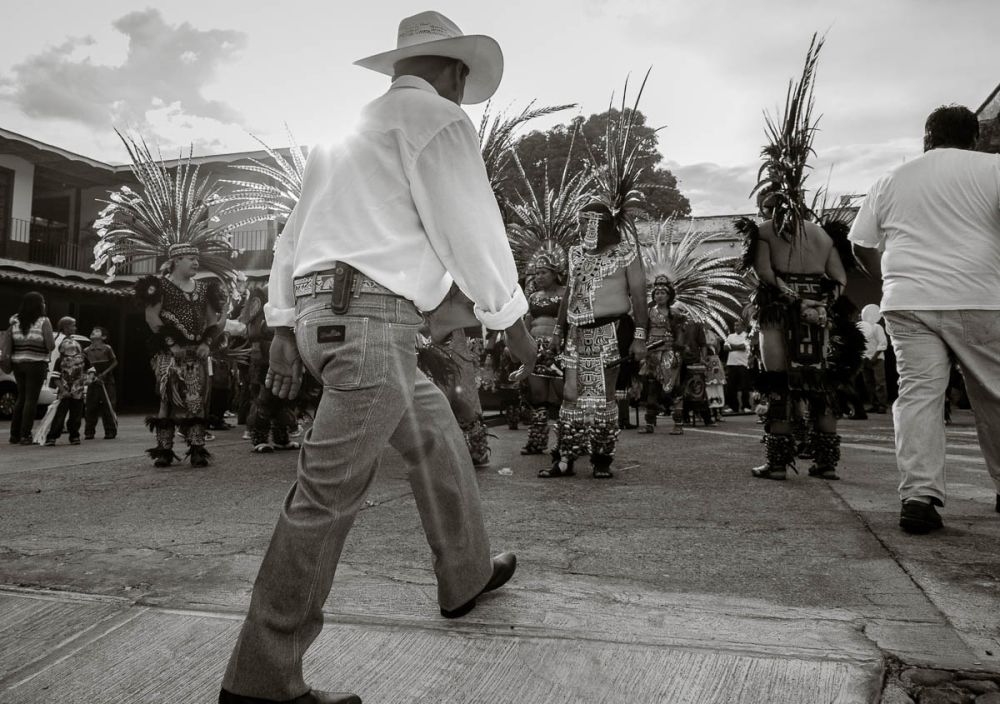 Man walking through Aztec dancers before the procession for Our Lady of the Rosary in Ajijic.