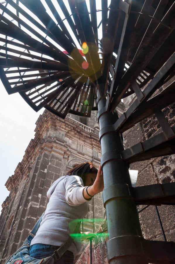 A woman walks up the staircase to get to the roof the Metropolitan Cathedral in Mexico City.