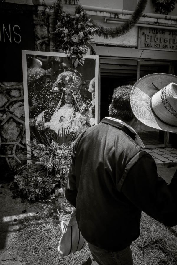 Man lifting his hat while passing image of La Virgen de la Merced in San Cristóbal de las Casas