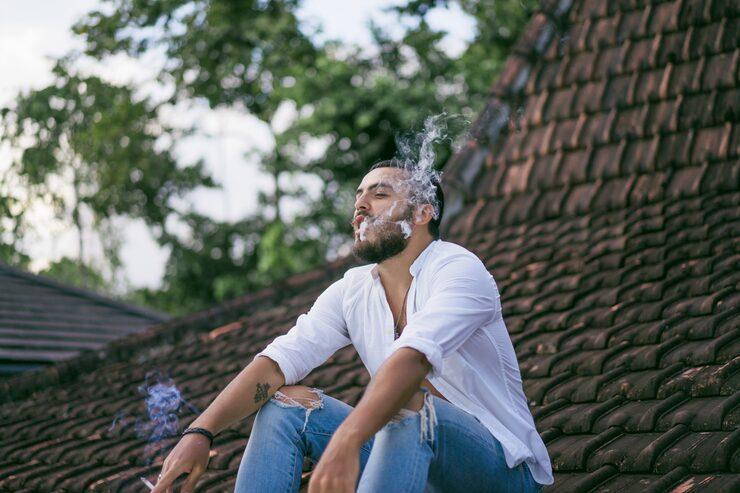 bearded man smoking on the roof