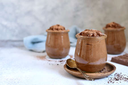 Delicious chocolate mousse in a vintage jars on a light slate, stone or concrete background.