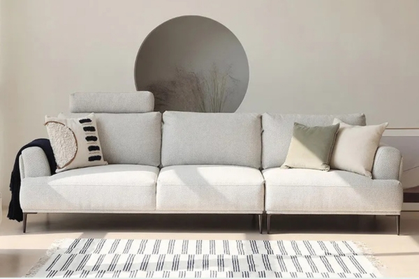 A cream-coloured 3-seater sofa made of fabric, solid wood frame, with well-stuffed backrests, and supported by carbon steel legs.