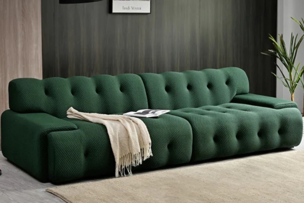 Green fabric 3-seater tufted sofa with curvy edges.