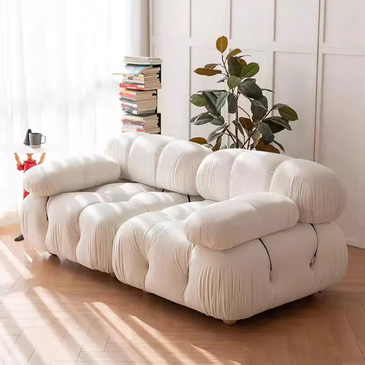 White 2-seater sofa upholstered in soft fabric with tufted design and wooden legs.