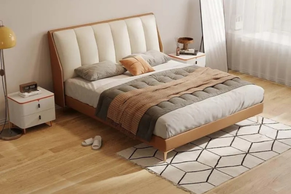 A king size bedframe with a headboard, supported by sturdy steel legs, covered in orange and cream leatherette.