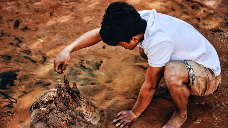 Young barefoot man playing with mud