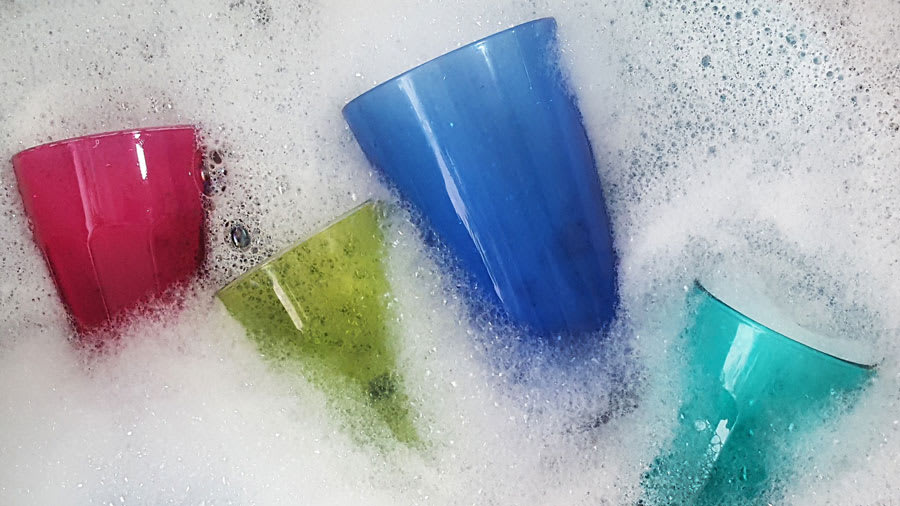 Colorful cups floating in a sink full of soap