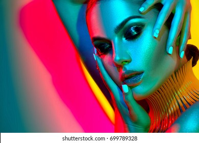 High Fashion model woman in colorful bright lights posing in studio, portrait of beautiful sexy girl with trendy make-up and manicure. Art design, colorful make up. Over colourful vivid background.