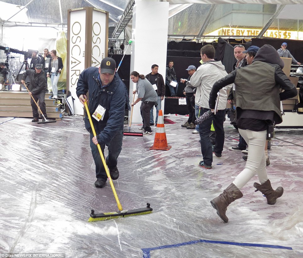 And... action: Organisers scrambled to unveil the red carpet at the last minute after keeping protective cover on it during the heavy Los Angeles downpours