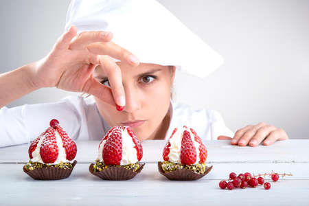 Woman pastry chef decorates small strawberry cakes Stock Photo