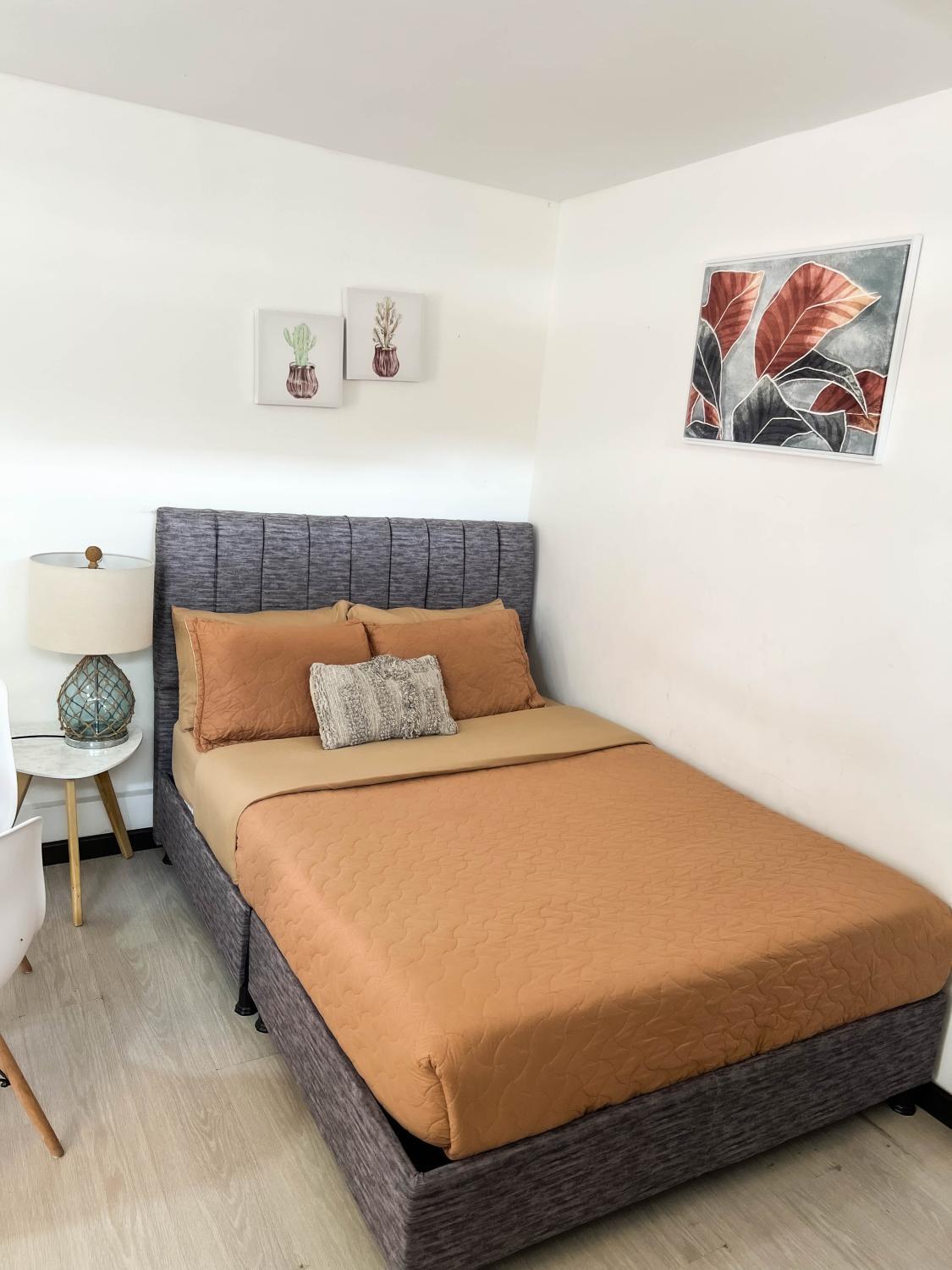 Cama anaranjada en una habitación de apartaestudio