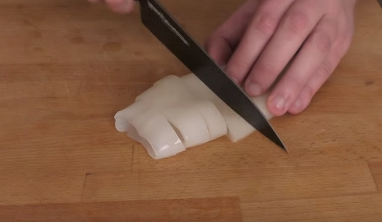 Нарезаем кальмары кольцами.