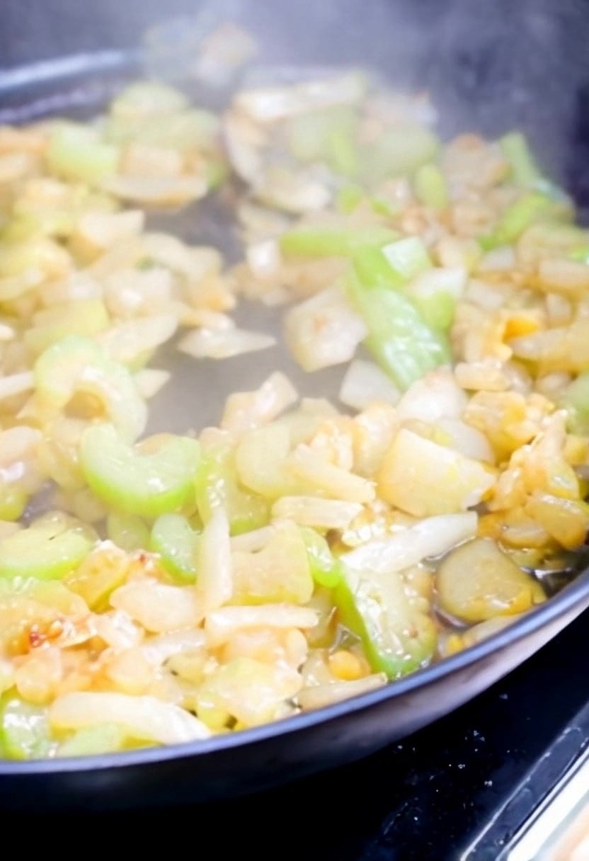 Onions and celery cooking in butter in a frying pan