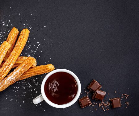 Churros with liquid chocolate. churro - fried dough pastry with sugar powder on black background.