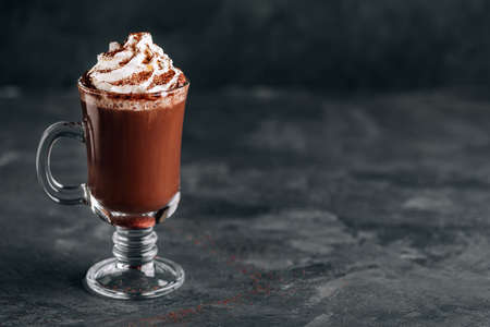 Hot chocolate cocoa with whipped cream in glass on dark background, copy space. traditional drink for christmas.