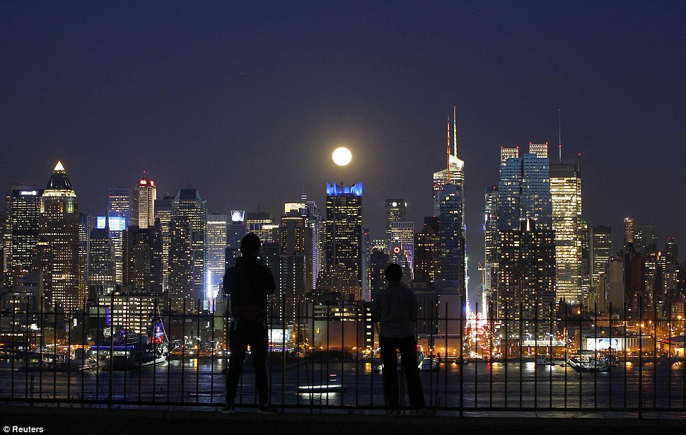 Moonlighting: People watch the full moon as it rises over the skyline of New York City near 42nd Street as seen across the Hudson River in Weehawken