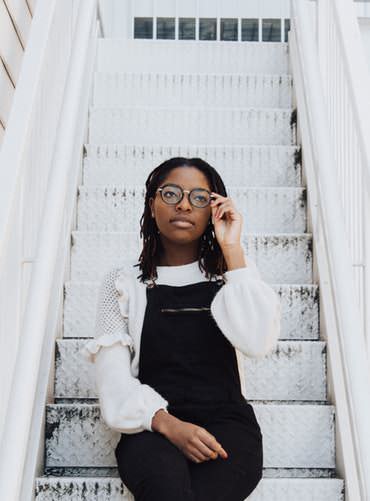 A girl wearing glasses sitting on stairs